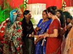 Meeting guests while the garlanded bride&nbsp;watches